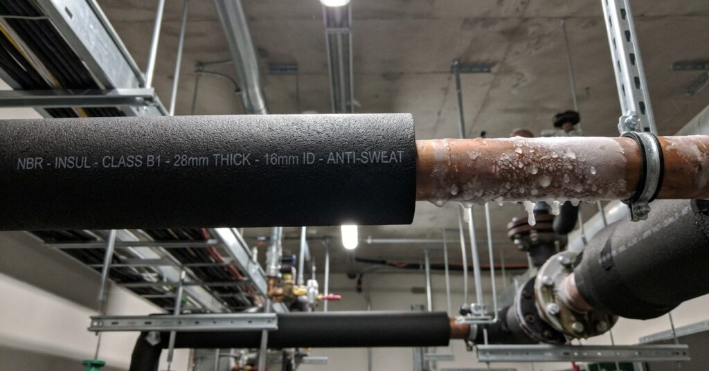 Closed-cell NBR foam insulation tube installed on commercial HVAC chilled water copper pipes preventing condensation