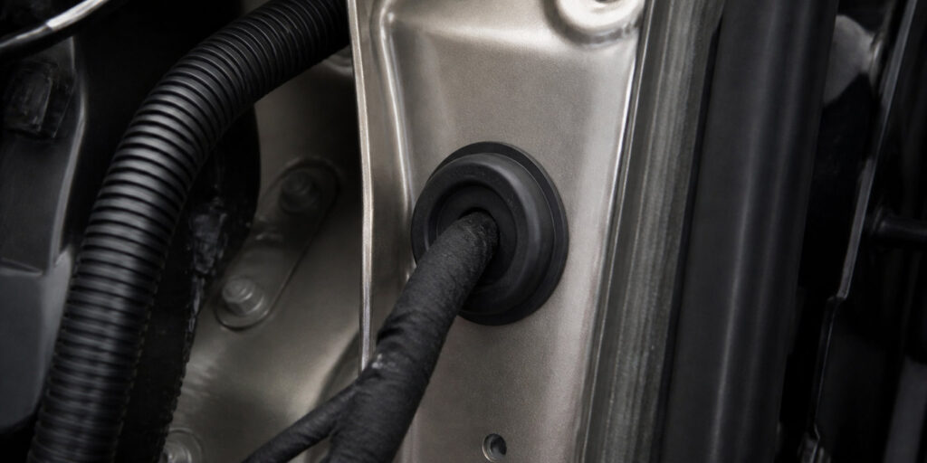 Automotive rubber grommet installed around wiring in a vehicle body panel
