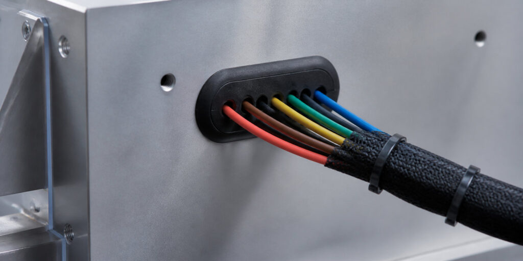Wire harness rubber grommet protecting multiple wires through a panel